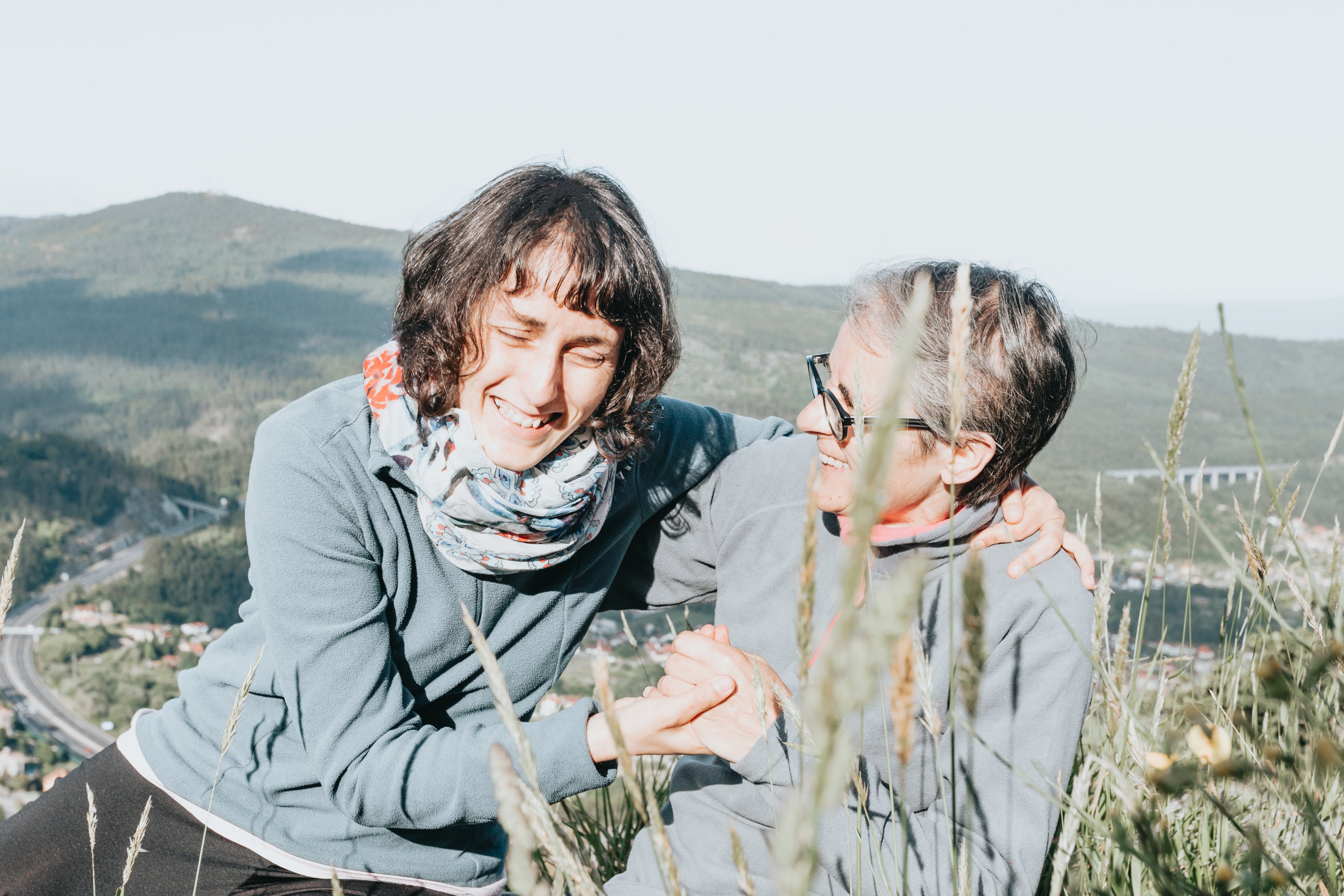 files/two-women-laugh-together-while-sitting-around-tall-grass.jpg